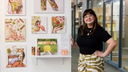 A student standing proudly by her creative work mounted on a white board.