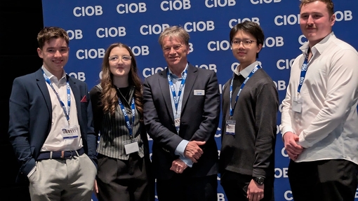 A group of smiling students standing proudly against a branded background.