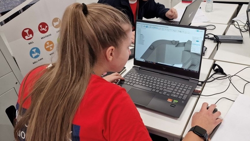 Two students working on their laptops in a workshop evnvironment.
