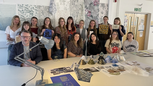 A group of people looking at a camera with some holding up artwork