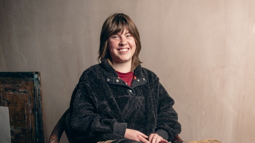 A student sitting on a chair with a table close by.