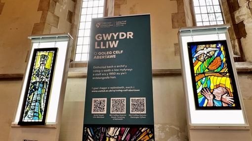 Two stained glass panels in a church building with a branded banner in between.