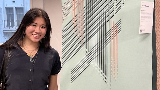 A girl smiling next to artwork on display
