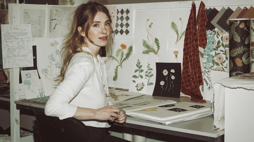 A person sitting on chair in front of desk with drawings of flowers in front of them