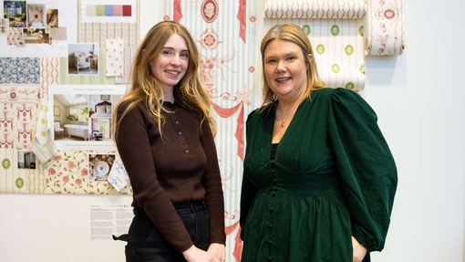 Two people standing in front of designs on wall