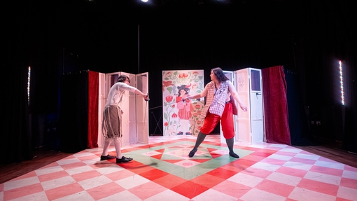 Two people in costumes sword fighting on chequered floor