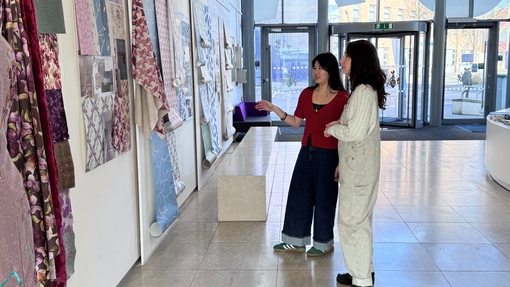 Two students viewing colourful art work on a wall.