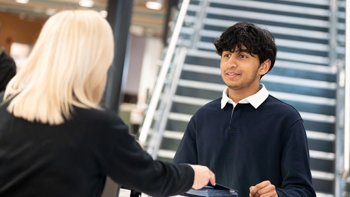 Student receiving a pamphlet from a member of staff