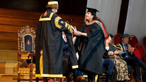 A graduate crossing the stage shaking hands with the Vice-Chancellor