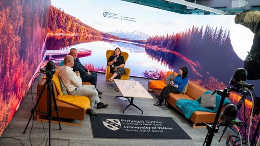 Four people seated in an immersive room with recording equipment in the foreground.