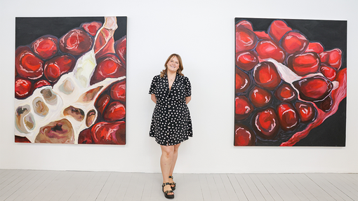 student in front of art work smiling