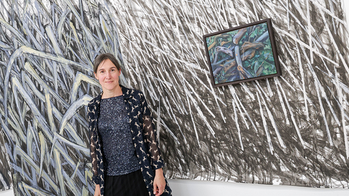 student in front of art work smiling