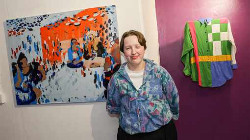 student in front of art work smiling