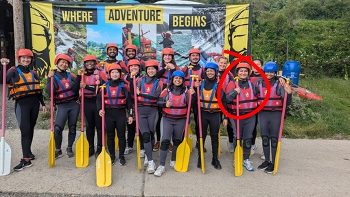 A group of people in wetsuits holding canoe paddles
