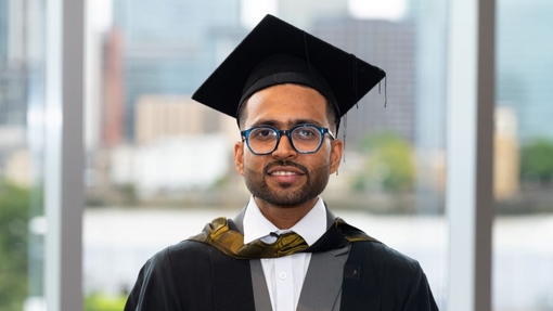 A smiling and proud graduate standing in his cap and gown.