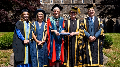 Group photo outside old college building wearing graduation robes are Mererid Hopwood, Lowri Lloyd, Catrin Stevens, Elwen Evans and Emlyn Dole
