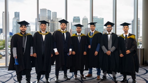 A group of graduates standing proudly in their cap and gowns.