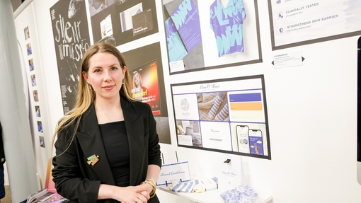 Woman in blazer standing in front of displayed graphic design work