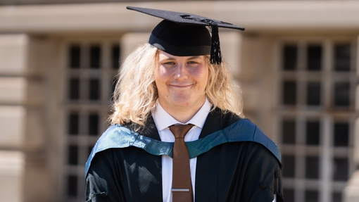 A graduating student smiling at camera