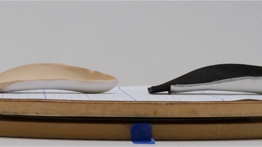Two curved shaped soles on a thin wooden base.