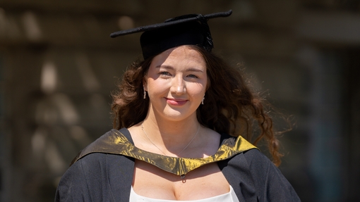 A woman smiling for camera dressed in cap and gown
