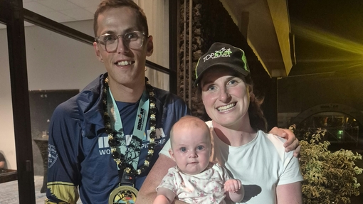 Guto Morgan wearing his Ironman Championship medal with his wife and daughter