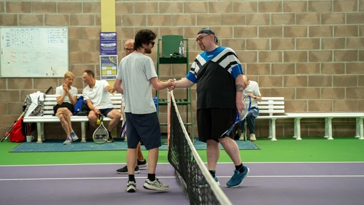 Two men at tennis court shaking hands