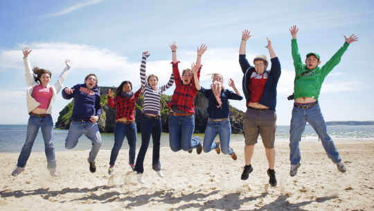 Group of students jumping on the beach