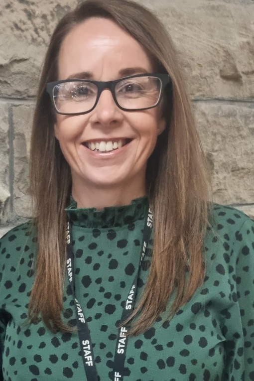 Ceri Littlewood yn gwenu'n uniongyrchol ar y camera.