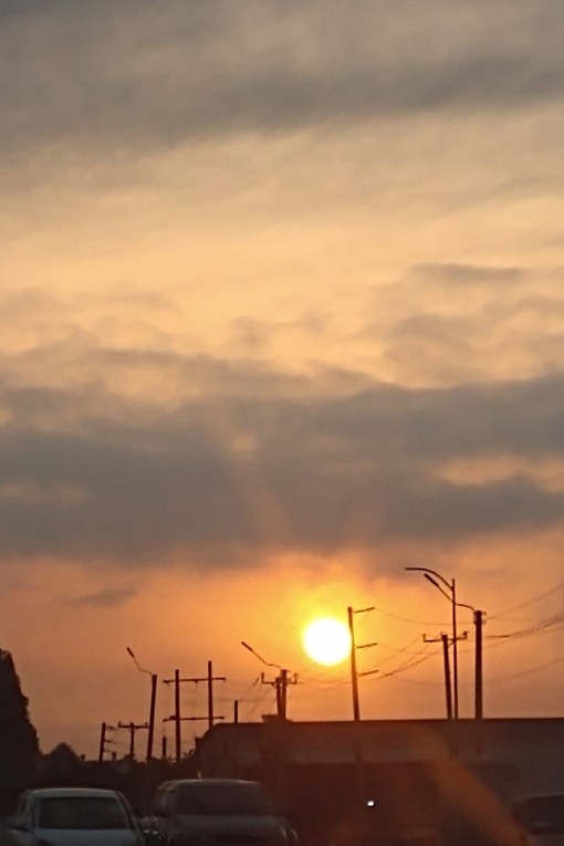 A golden red sunset sky with only the tops of buildings outlined in the fading light.