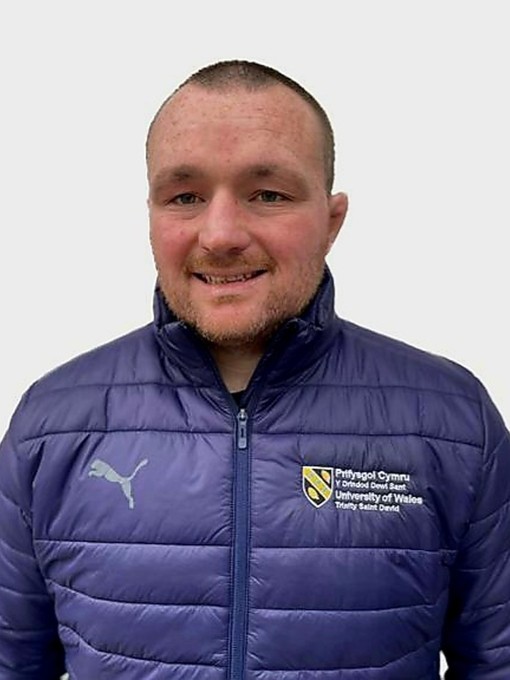 Ken Owens yn gwisgo siaced borffor bwfflyd y Drindod Dewi Sant.