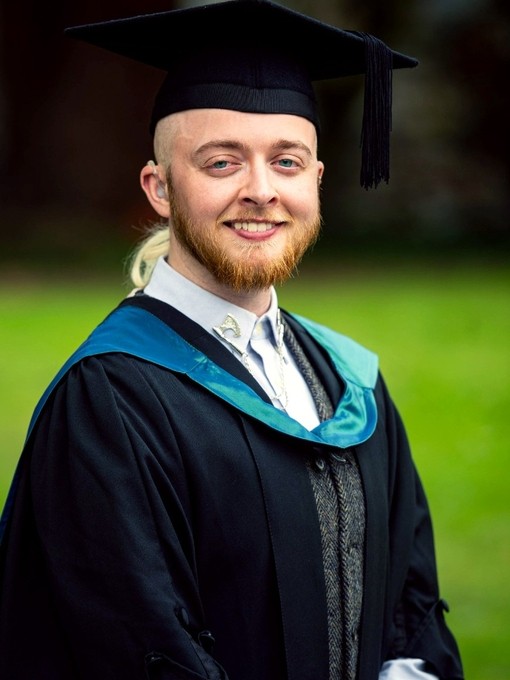 Aeron Jones yn gwisgo’i ŵn a’i het raddio.