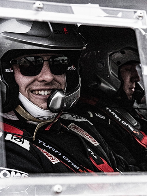 a person sitting in a rally car smiling