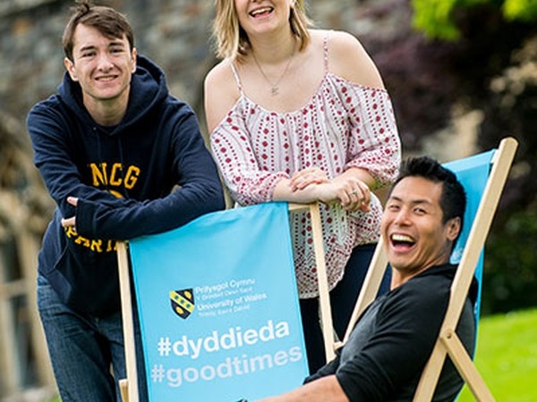 Carmarthen students smiling with branded deckchairs. 