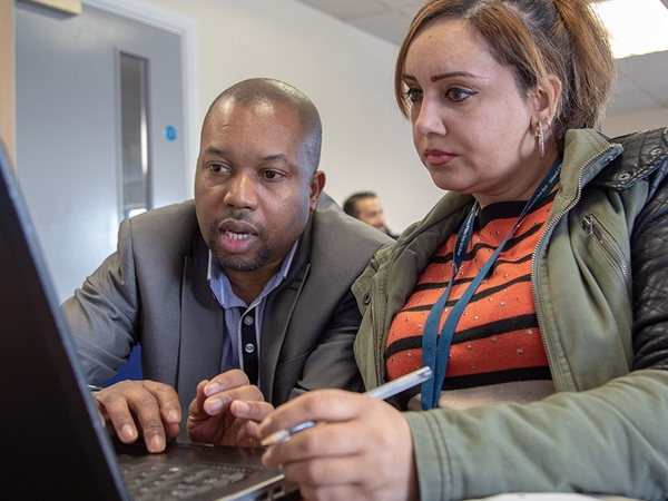 Staff member and student looking at a laptop