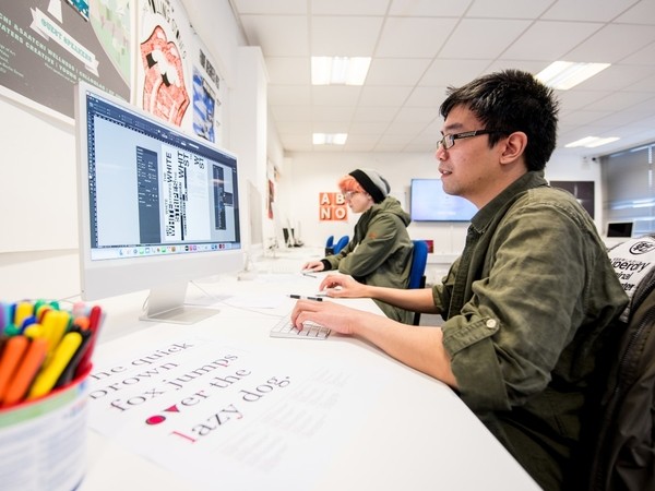 A student uses an Apple Mac with a widescreen monitor. 
