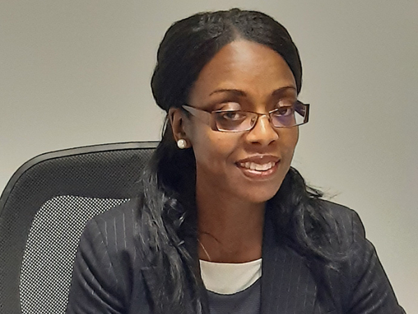 Wearing a suit jacket and sitting in an office chair, Dr Diola Bijlhout smiles towards the camera.
