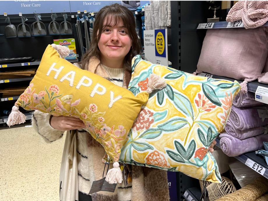 Girl smiling holding up two cushions