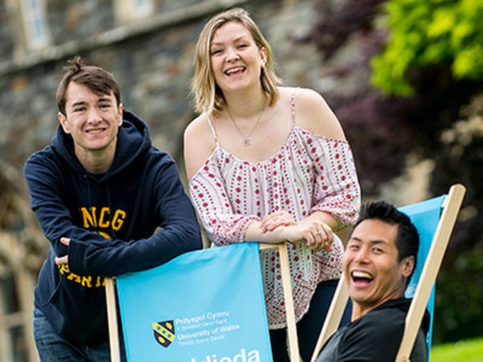 Carmarthen students smiling with branded deckchairs. 