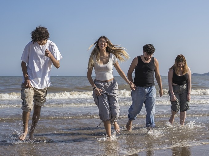 four students on beach playing in shallow water