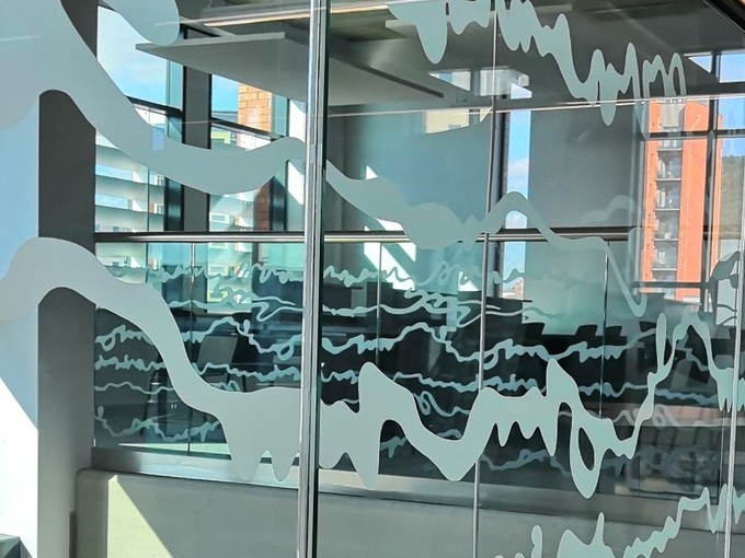 Armchair on a mezzanine in front of a glass panel decorated with white wriggly lines.