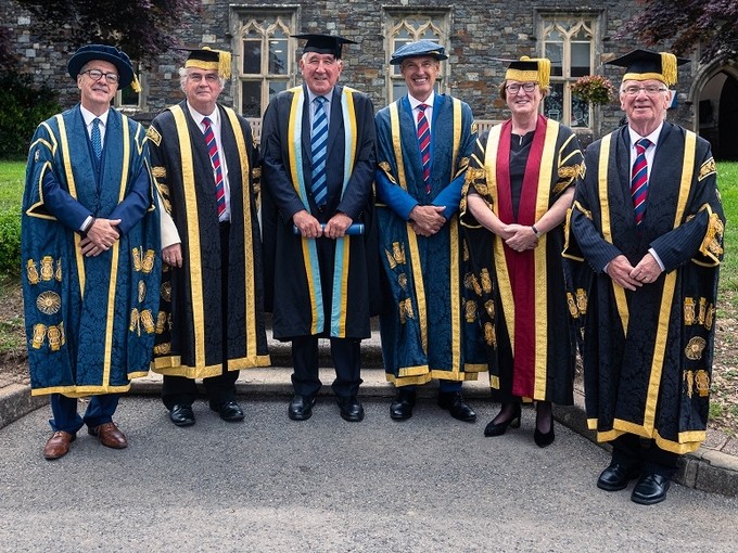 Eifion Griffiths gydag uwch aelodau’r Brifysgol i gyd yn gwisgo dillad academaidd llawn.