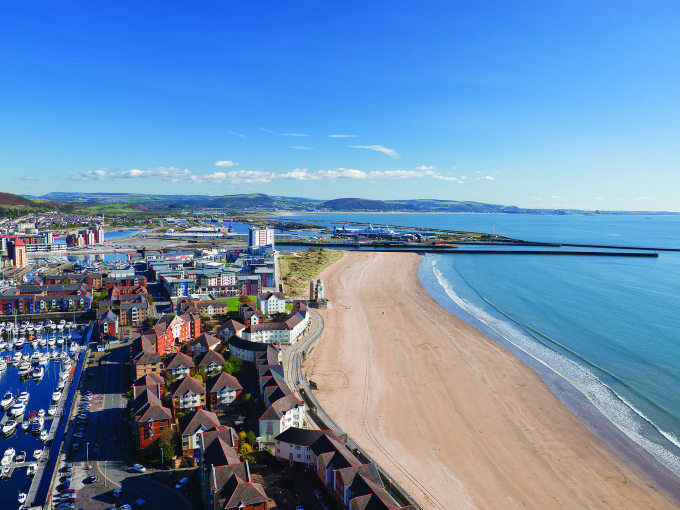 Llun o Abertawe yn cynnwys y traeth a’r harbwr o’r awyr