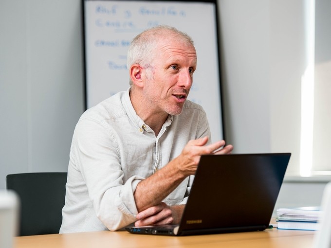 Aelod o staff ynghanol trafodaeth gyda gliniadur o'i flaen