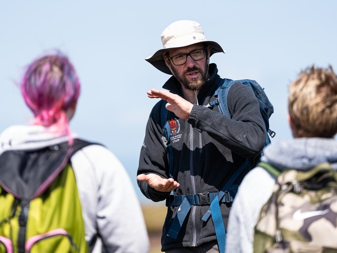 Three people in discussion and wearing backpacks