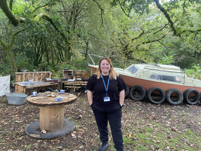 Woman standing in forest with boat behind her