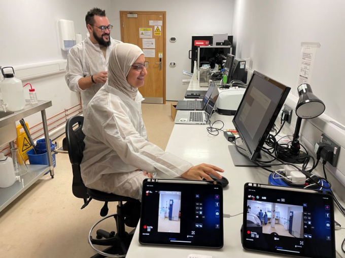 A man and woman working in a lab environment surrounded by computer screens.
