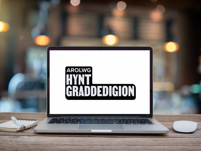 gliniadur ar fwrdd gyda 'Arolwg Hynt Graddedigion' ar y sgrin