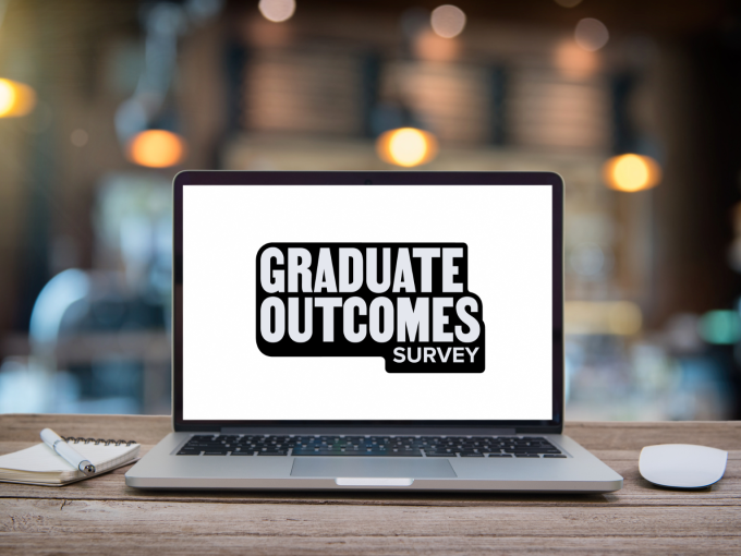 a laptop on a table with 'Graduate Outcomes survey' on screen