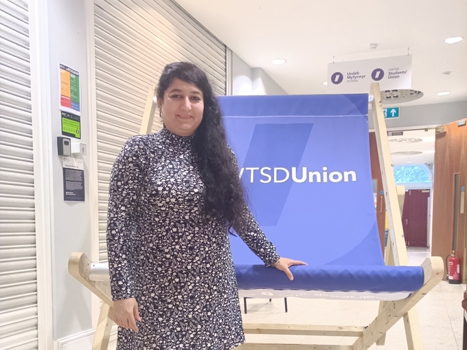 A woman standing in front of a giant deck chair saying 'Student Union'